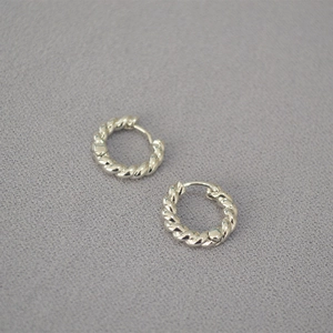 Gros plan de boucles d'oreilles créoles argentées avec texture torsadée vintage