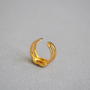 Detail of gold-plated woven knot open ring with smooth polished brass texture