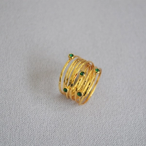 Close-up of handmade gold-plated multi-layer ring with hammered texture and green zircons