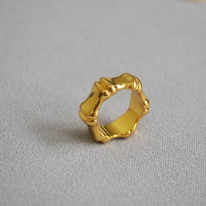 Macro shot of gold-plated bamboo joint style ring on a textured fabric surface