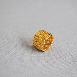 Macro view of gold-plated mesh texture and hollow woven design on wide band ring