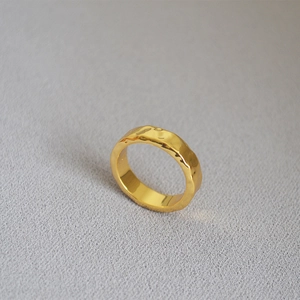 Detailed close-up of textured gold-plated brass ring with water ripple surface design