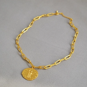 Dettaglio macro della collana a catena dorata con ciondolo a moneta romana in rilievo