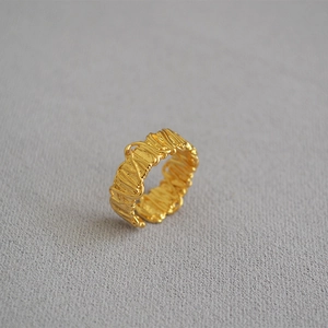 Macro detail of gold textured open ring featuring modern woven metal craftsmanship