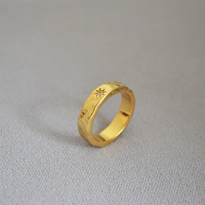 Macro shot of gold-plated North Star ring with hammered texture and a single zircon stone