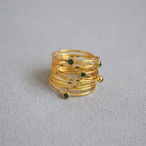 Macro view of gold hammered texture rings featuring layered design and green gemstones