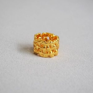 Macro shot of chunky gold-plated brass ring with textured multi-layer woven design