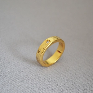 Macro detail of gold plated brass ring with water ripple texture and North Star motif