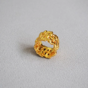 Detailed view of wide woven gold-plated brass ring with irregular mesh pattern