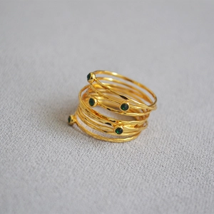 Macro detail of hammered gold rings set featuring emerald green zircon in bezel setting