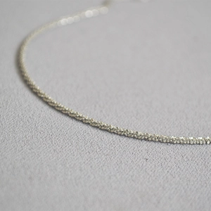 Macro detail of minimalist brass necklace chain with fine 18k gold starry texture