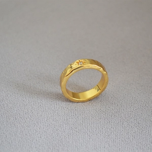 Detail of gold hammered brass ring featuring an eight-pointed star and zircon stone