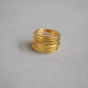 Macro detail of multi-layered gold ring featuring handmade hammered texture and layered style