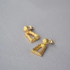 Detail of gold geometric hollow earrings featuring unique hammered texture finish