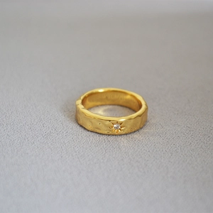 Macro shot of gold-plated ripple ring featuring a star-set crystal and hammered texture