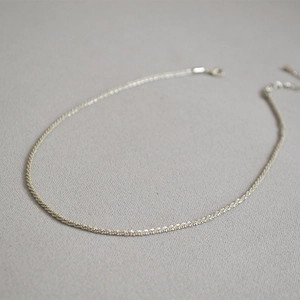 Close-up of a silver starry chain necklace with adjustable lobster clasp on grey texture