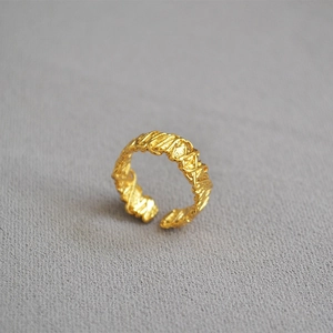 Macro shot of gold-plated open ring with intricate twisted woven texture and vintage finish