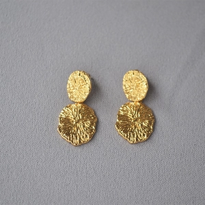 Macro view of gold earrings with handmade hammered texture on double metal discs