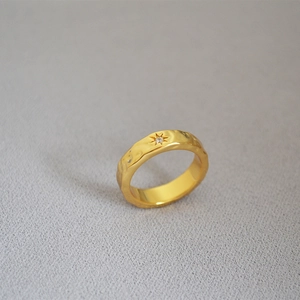 Detail of gold-plated brass ring with wavy texture and starburst inset gemstone