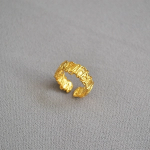 Macro shot of gold filigree woven design with rough handmade texture on an open ring