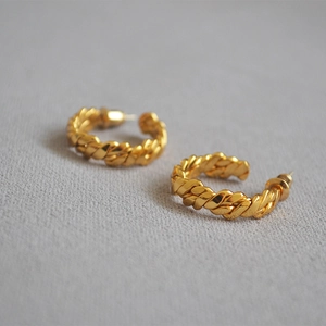 Close-up of gold-plated woven hoop earrings with intricate braided texture design