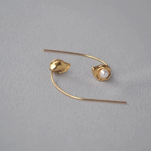 Close-up of gold-plated long hook pearl earrings featuring delicate bud-shaped details