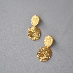 Detailed close-up of textured gold circular earrings with unique hammered metal finish