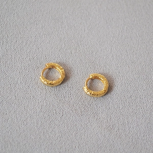 Detail shot of golden hoop earrings with hammered texture and textured metal finish