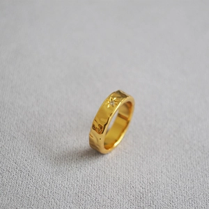 Detail of gold-plated brass ring featuring hammered water ripple texture and North Star