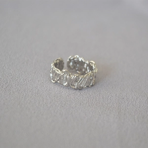 Close-up of silver ring with woven texture and industrial-style adjustable open band