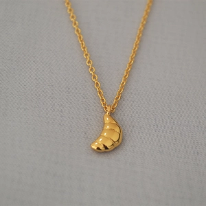 Vue détaillée du pendentif croissant doré au fini miroir et chaîne minimaliste raffinée