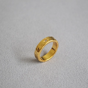 Macro shot of gold-plated brass ring featuring wavy texture and North Star detail