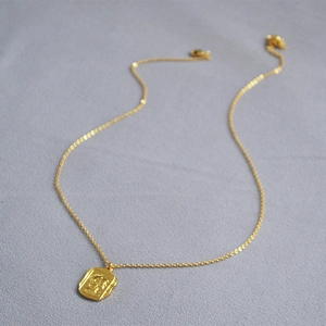 Close-up of gold Roman relief square coin pendant on a fine O-chain necklace