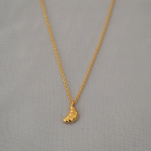 Collier avec pendentif croissant doré élégant et chaîne fine sur fond gris texturé