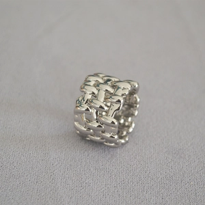 Macro shot of the irregular woven texture and polished silver finish on the wide band ring