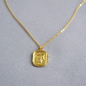Detail view of a vintage gold coin pendant with Roman relief and fine O-chain texture