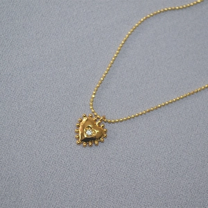 Detail view of heart pendant necklace with center zircon and gold ball chain texture