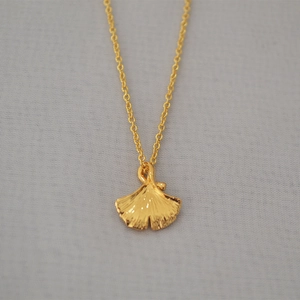Detailed view of golden ginkgo leaf pendant with fine textures on a minimalist chain