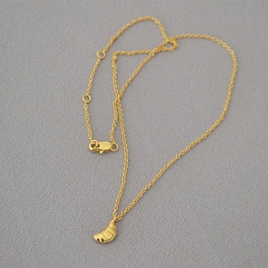 Détail du pendentif croissant doré avec finition polie sur une chaîne délicate et fine