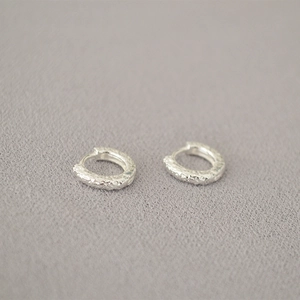 Minimalist silver hoop earrings with hammered texture and rustic lava finish
