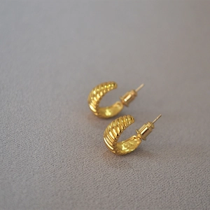 French style gold-plated croissant hoop earrings with minimalist screw texture on grey background