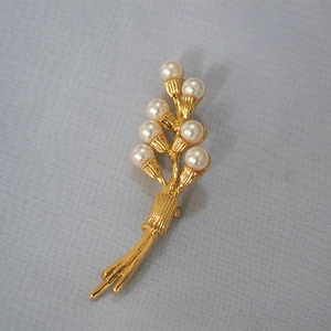Detail of vintage gold flower brooch with seven pearls and textured metallic finish