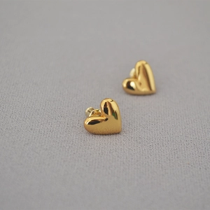 Detailed view of heart-shaped gold studs with a high-polished metallic finish
