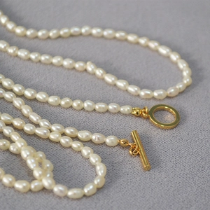 Vue macro d'un collier de perles de riz d'eau douce avec fermoir en T doré élégant