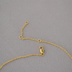 Macro shot of gold-plated ginkgo leaf necklace showing lobster clasp and adjustable links