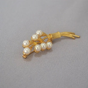 Macro detail of vintage gold pearl flower brooch with textured branch cluster design