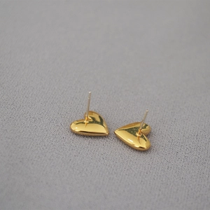 Macro shot of polished gold-plated heart earrings with a shiny mirror-like finish