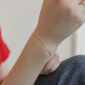 Close-up of minimalist thin silver snake chain bracelet worn on female wrist