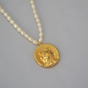Detail of freshwater rice pearls and gold coin pendant with embossed cat head design