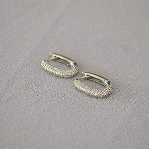 Macro shot of silver U-shaped earrings featuring micropave set sparkling cubic zirconia stones